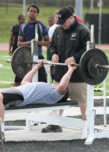 Sachem assistant coach Mike Marrato spots a player on the 185-pound bench press. Credit Ray Nelson